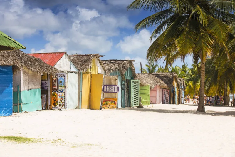 A sand path running between the painted wooden houses of Mano Juan village