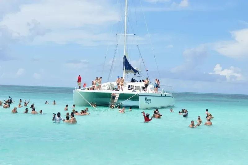Travelers standing waist-deep at the Natural Pool sandbar a kilometer from shore